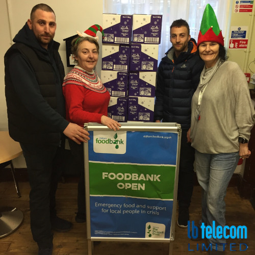 a group dressed in Christmas attire stood around a foodbank sign