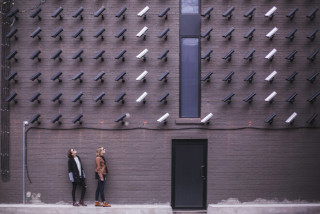 two women looking up at a wall of cctv camera